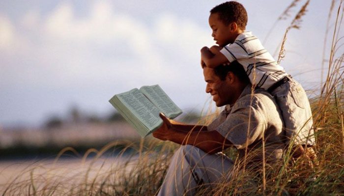 A father reading the Bible with his son. (pinterest)